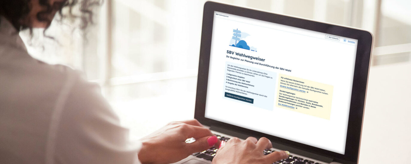 Das Foto zeigt eine Frau an einem Notebook. Der Blick fällt über ihre Schulter auf das Display. Darauf ist ein blauer Wegweiser über einem mehrzeiligen Text zu sehen, darunter ein dunkleblauer Button.