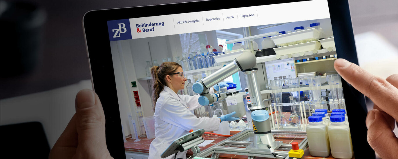 Das Foto zeigt zwei Hände, die ein Tablet halten. Auf dem Display ist ein Laborarbeitsplatz zu sehen. Eine junge Frau mit langen Haaren und weißem Kittel arbeitet gemeinsam mit einem Roboter aus glänzendem Edelstahl.