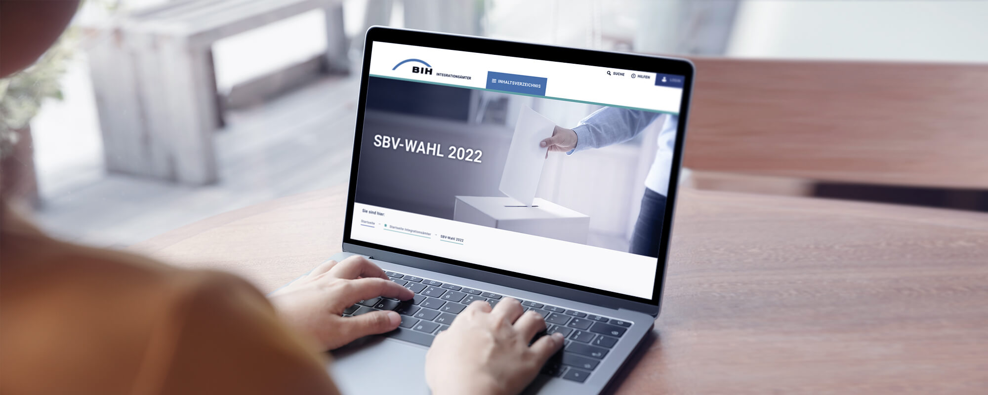 Eine Frau sitzt an einem Laptop mit BIH-Portalseite zur SBV-Wahl 2022