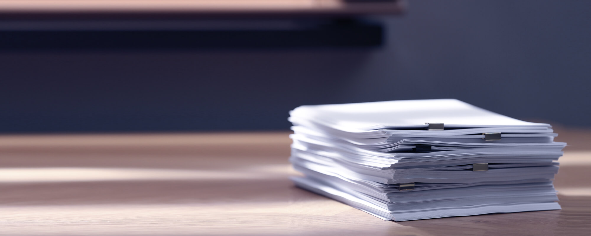 Papierstapel auf einem Schreibtisch| © shutterstock / New Africa Ein dicker Papierstapel liegt auf einem Schreibtisch.
