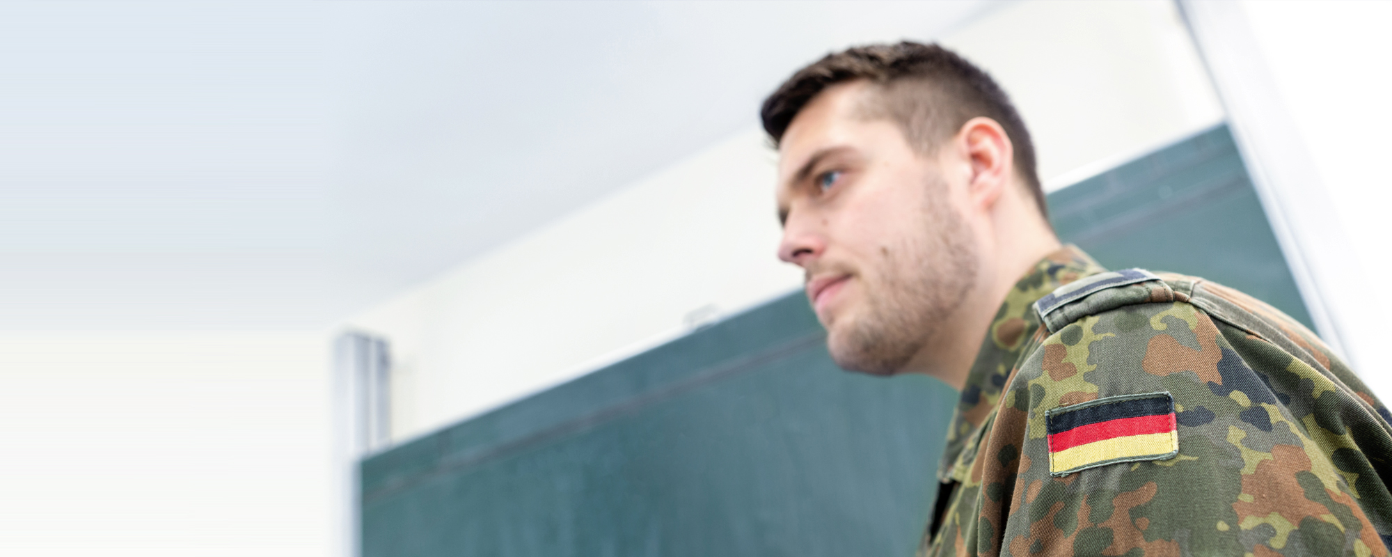 Ein junger Bundeswehrsoldat steht vor einer Tafel.