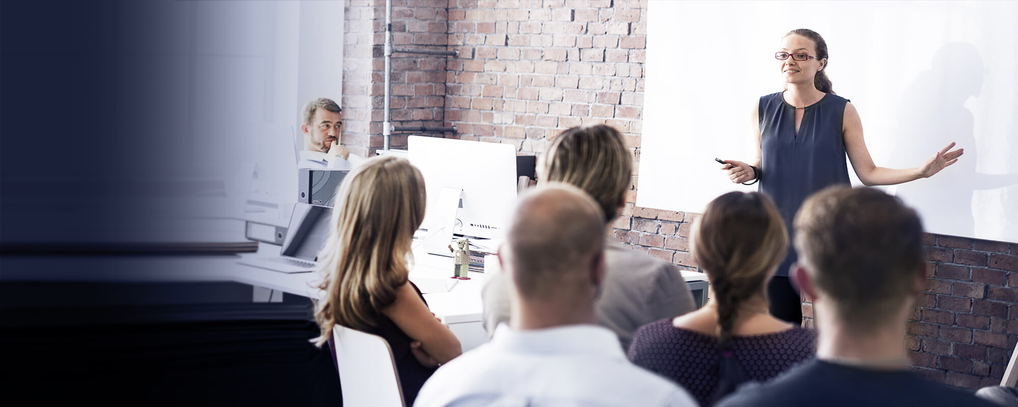 Eine Dozentin steht vor einer weißen Tafel und hält ein Seminar ab