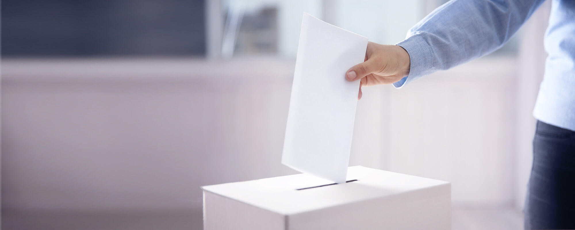 Ein Mann steckt einen Wahlschein in eine Wahlurne.