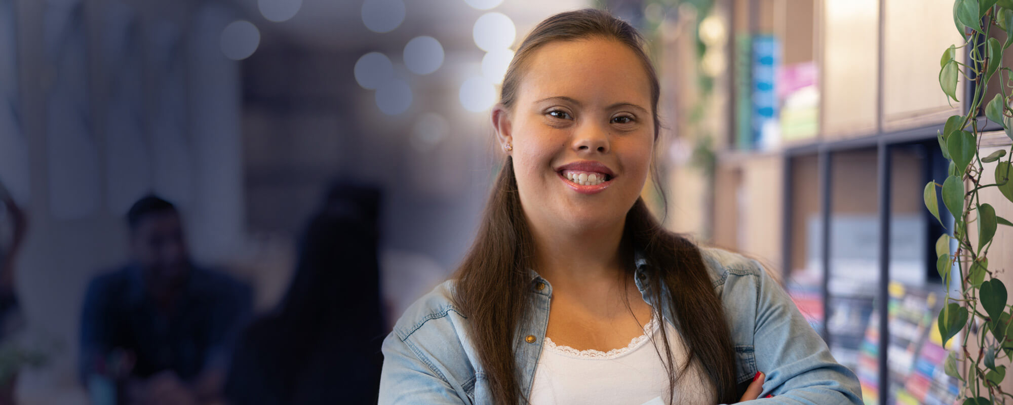 Eine Dame mit Trisomie 21 lächelt in die Kamera