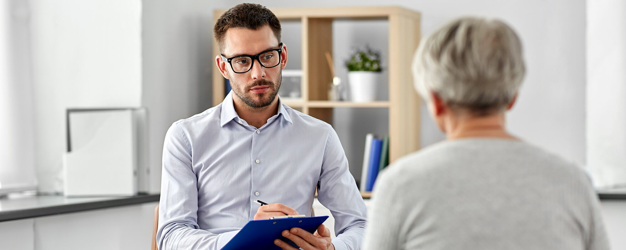 Psychosoziale Notfallversorgung im Unternehmen | © Ground Picture/Shutterstock Das Foto zeigt einen Therapeuten im Gespräch mit einer Frau. Der Blick fällt über die Schulter der Frau - sie ist nicht erkennbar.