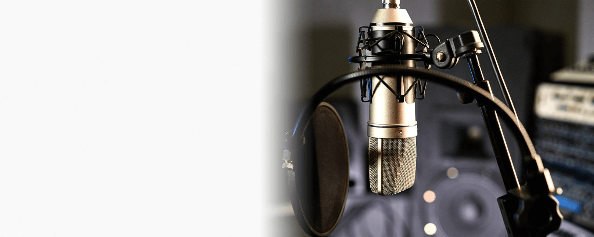 Das Foto zeigt im rechten Bildbereich ein Podcast-Studio. Im Vordergrund ist ein herangezoomtes Mikrofon zu sehen. Der linke Bildbereich ist weiß.tudiomik