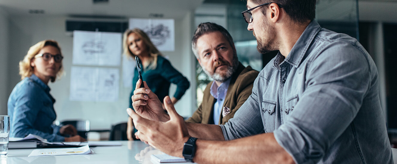 Die SBV stellt sich vor | © 2017 Jacob Lund/Shutterstock. No use without permission Zwei Männer und eine Frau sitzen an einem Konferenztisch und unterhalten sich. Im Hintergrund steht eine Frau vor einem Whiteboard.