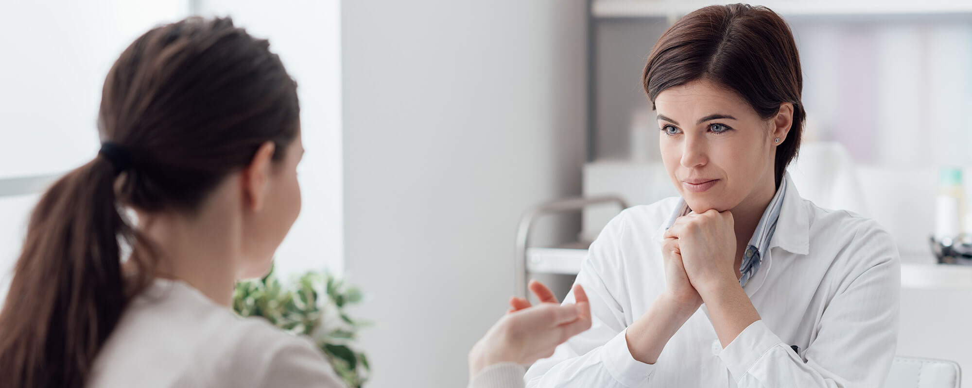 Zwei Frauen sitzen sich an einem Tisch gegenüber und unterhalten sich. 