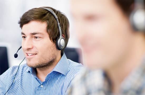 Zwei Männer mit Headset, die Person im Vordergrund unscharf gestellt.