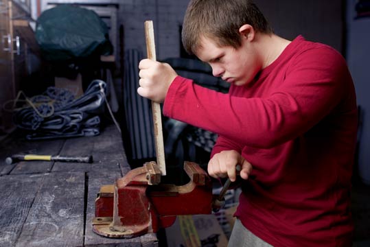 Junger Mann arbeitet an einem Schraubstock 