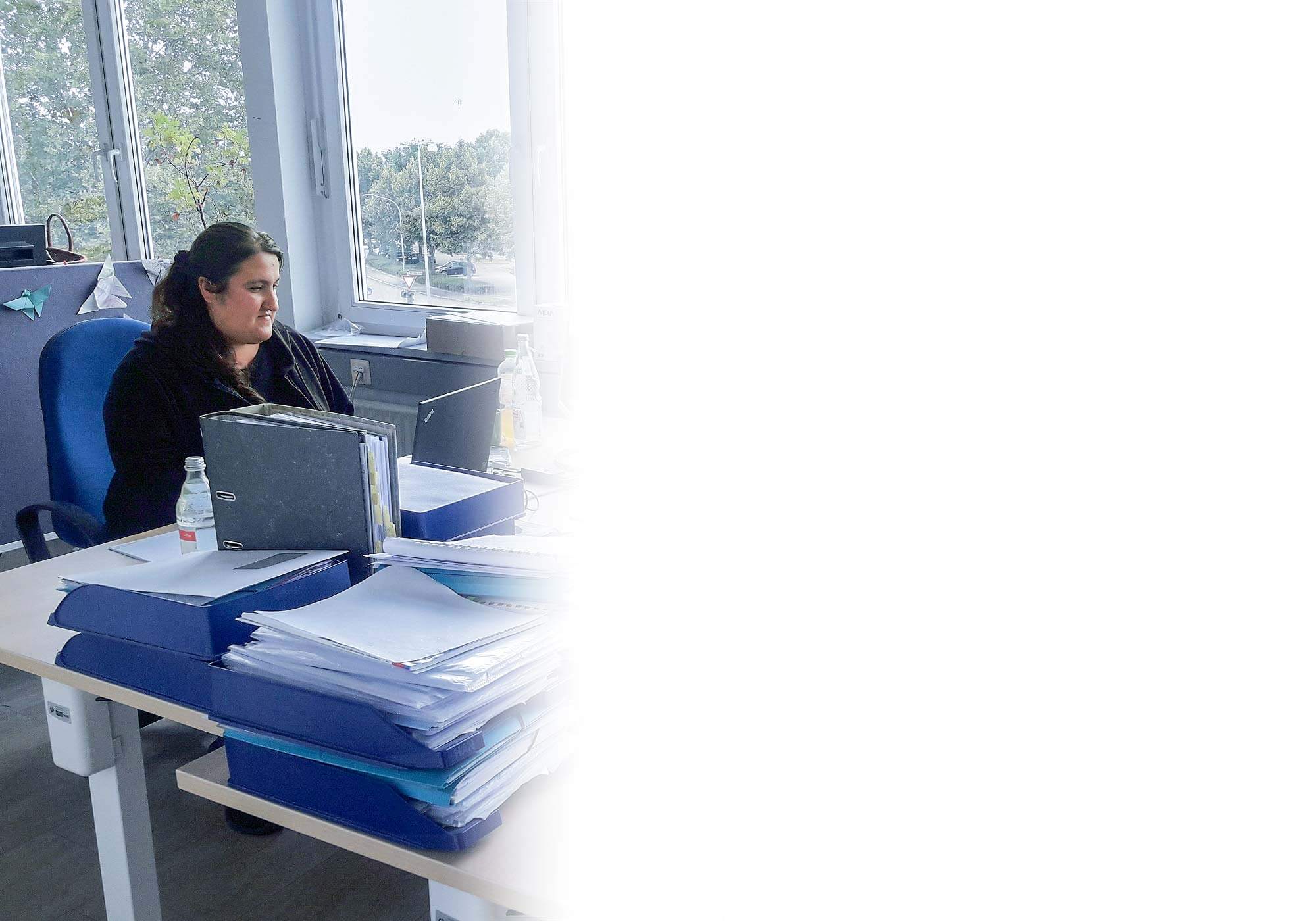 Eine Frau sitzt am Schreibtisch. Sie arbeitet am Laptop.