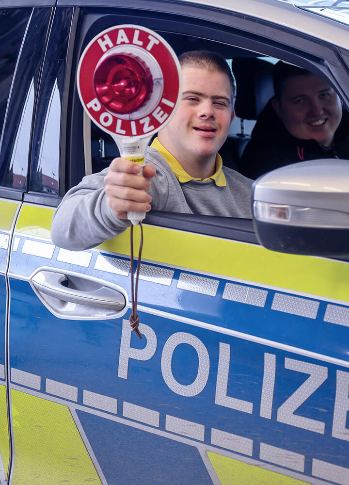 Dominik Thiele hält eine "Stopp"-Kelle aus einem Polizeiauto