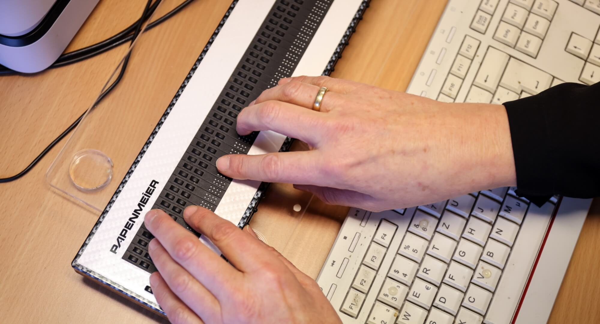 Hände tippen auf einer Braillezeile.