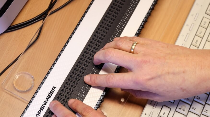 Hände tippen auf einer Braillezeile.