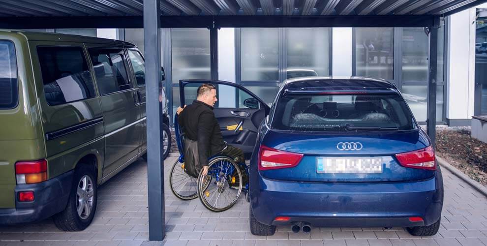 Mann in Rollstuhl steigt in ein Auto.