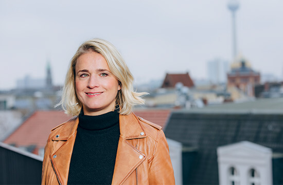 Frau Bentele im Portrait mit Stadtskyline im Hintergrund.