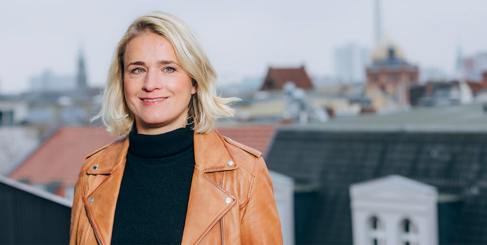 Frau Bentele im Portrait mit Stadt Skyline im Hintergrund.