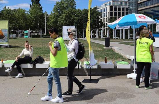 Aussenaufnahmen bei der Messe "Besser Sehen", gezeigt wird ein Parkour, der mit einem Blindenstock zu bewältigen ist. 