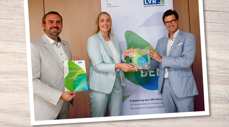Drei Personen bei der Übergabe der BEM-Prämie