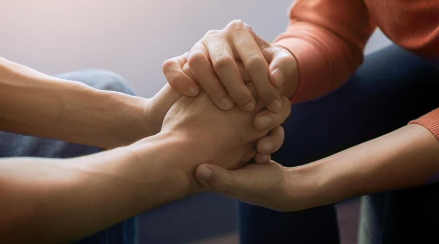 Psychische Erkrankungen begleiten | © shutterstock/Chanintorn.v Vier Hände halten sich fest.