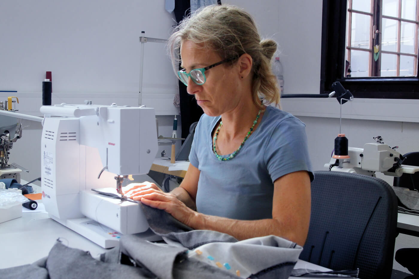 Das Foto zeigt eine Blauherz-Mitarbeiterin an der Nähmaschine.