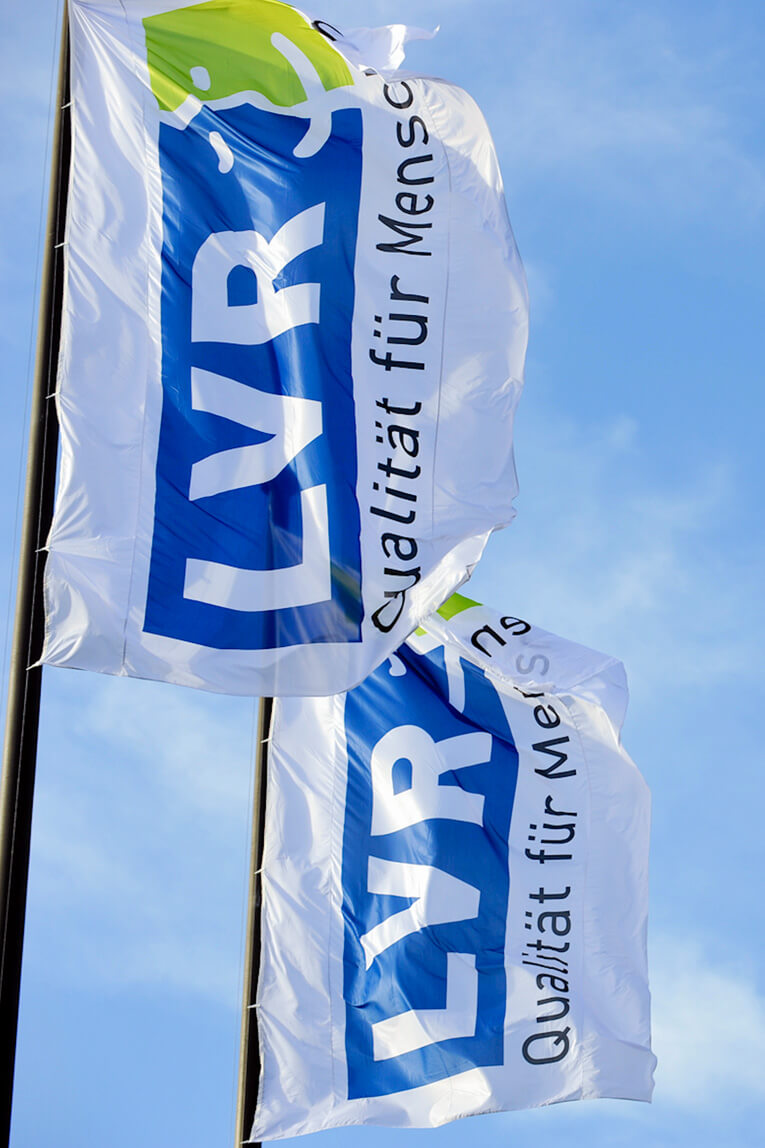 Zwei Flaggen mit dem Schriftzug „LVR – Qualität für Menschen“.