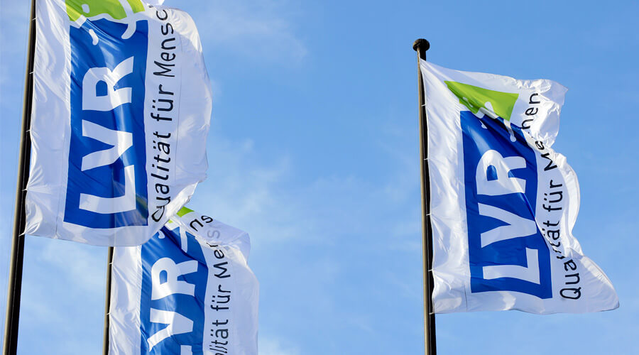 Drei Flaggen mit dem Schriftzug „LVR – Qualität für Menschen“.