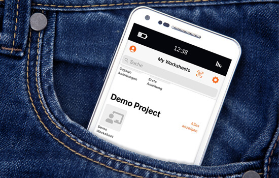 Ein Smartphone ragt aus einer Seitentasche einer Jeanshose heraus