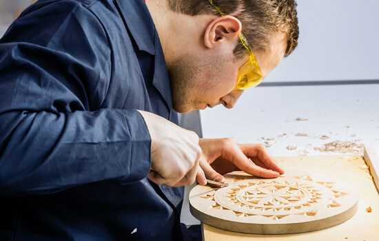 Ein Mann bearbeitet eine Holzscheibe in einer Werkstatt