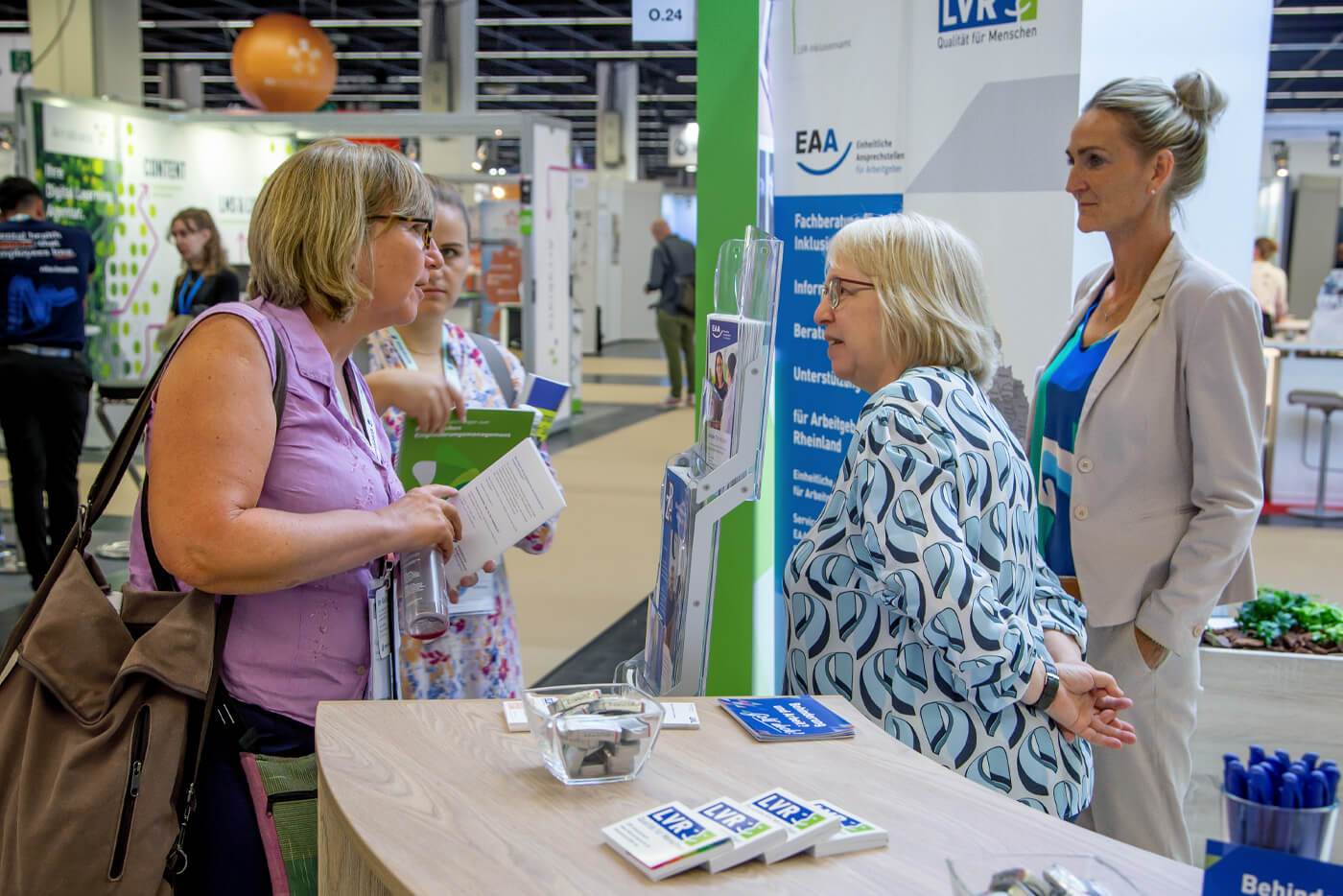 Zwei Mitarbeiterinnen beraten zwei Messebesucherinnen am LVR-Messestand.