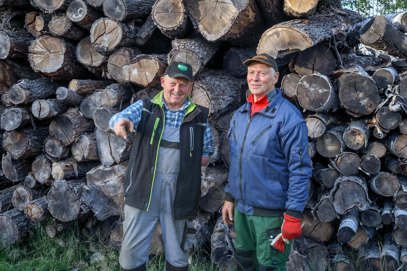 Leubner vor einem Stapel Baumstämme.