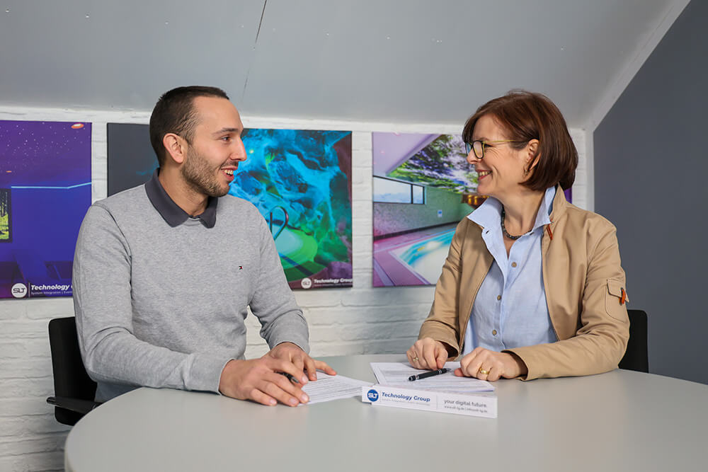 Benedikt Nöchel, Dorthée Schartz | © Rupert Oberhäuser Eine Mann und eine Frau sitzen sich an einem runden Tisch gegenüber und lächeln.