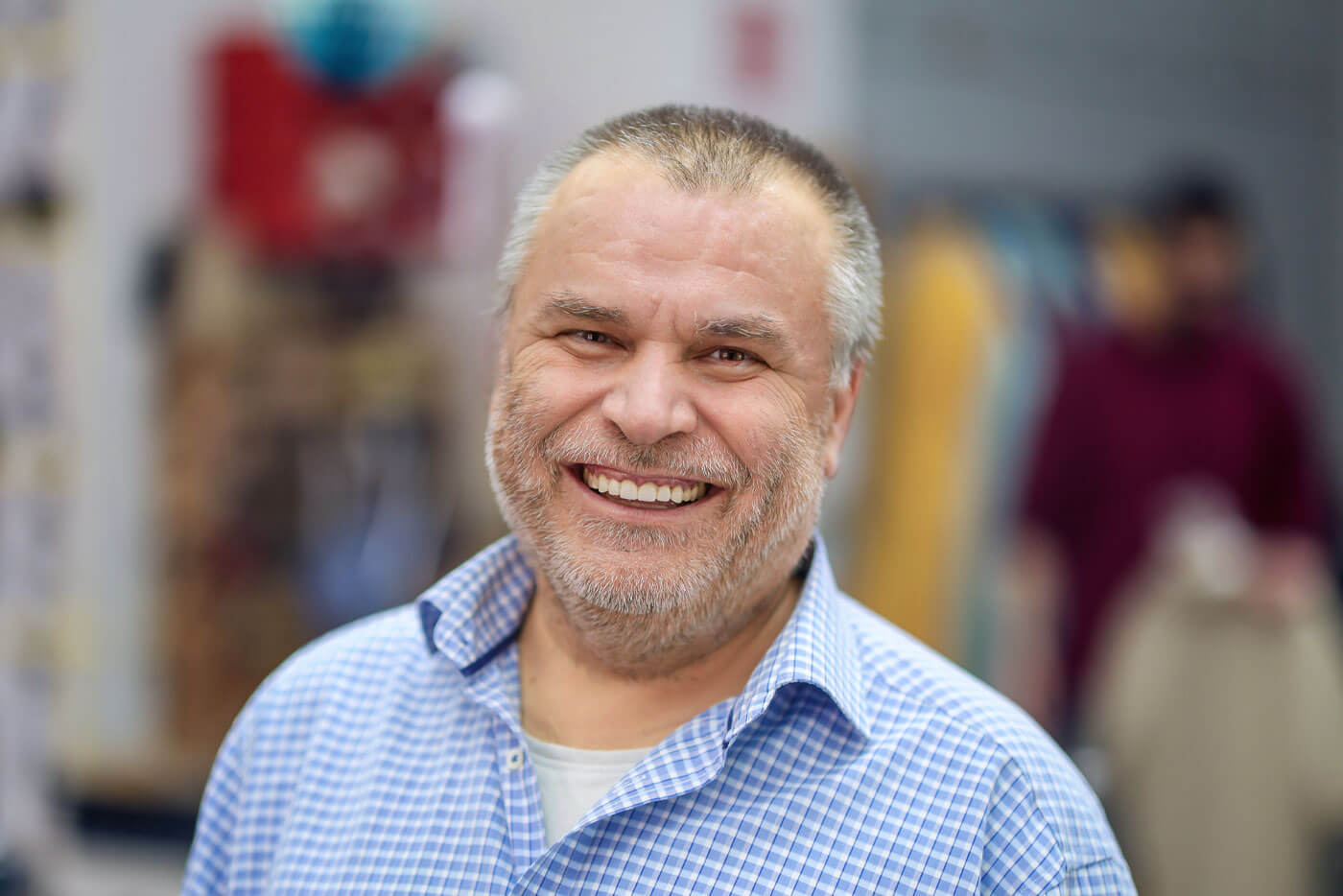 Der Herrenschneider Yusuf Aydoğan lächelt in die Kamera.