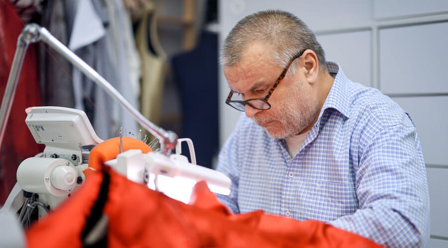 Der Herrenschneider Yusuf Aydoğan sitzt an der Nähmaschine.