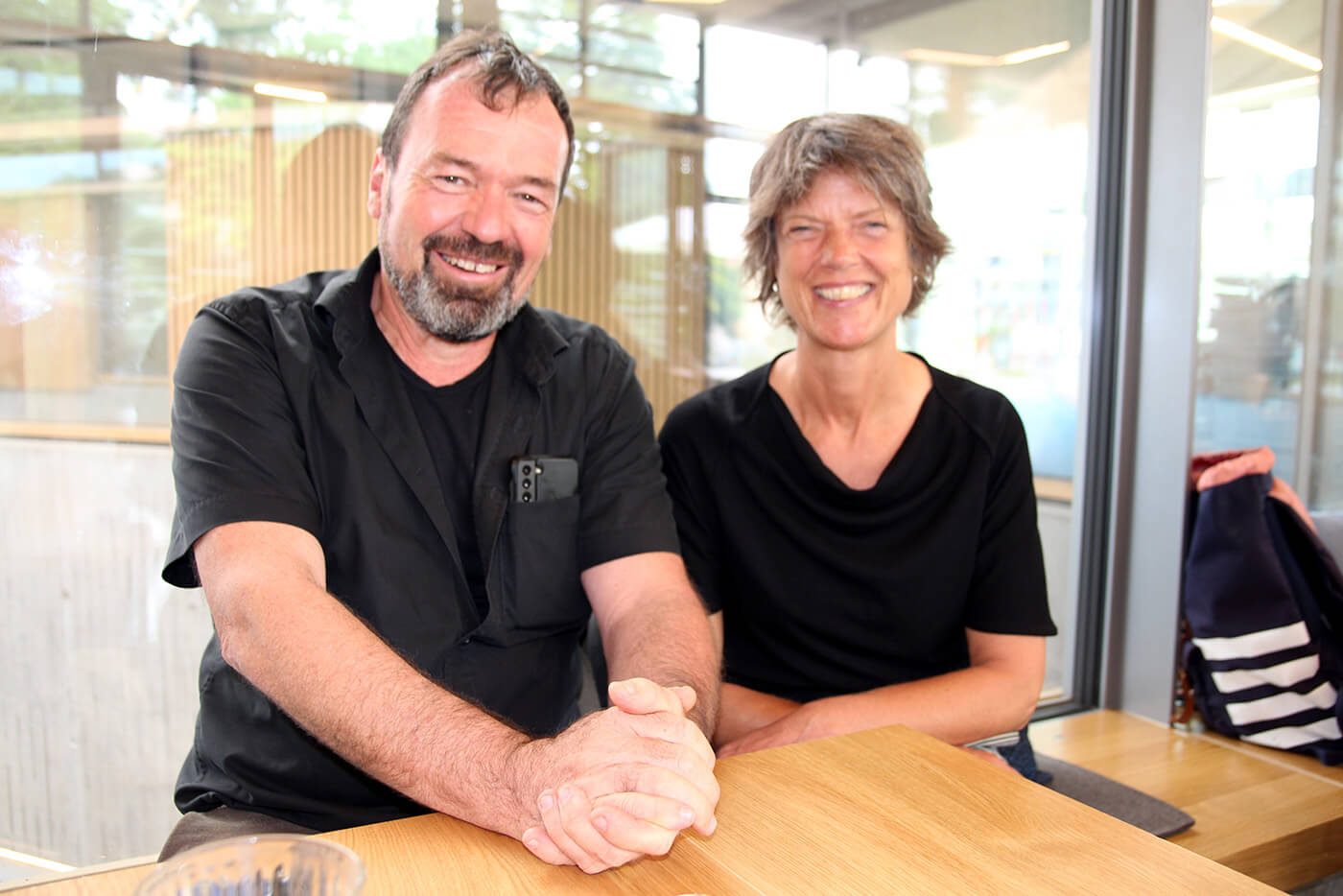 Marcus Hölz und Regina Gmelin stehen in schwarzen T-Shirts hinter dem Tresen ihres Cafés.