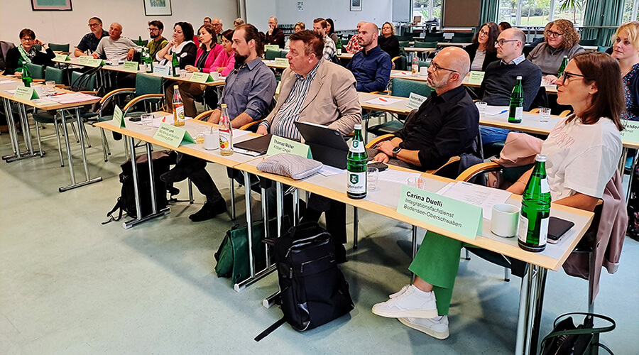 Die Teilnehmer der Tagung sitzen in Tischreihen und hören einem Vortrag zu.