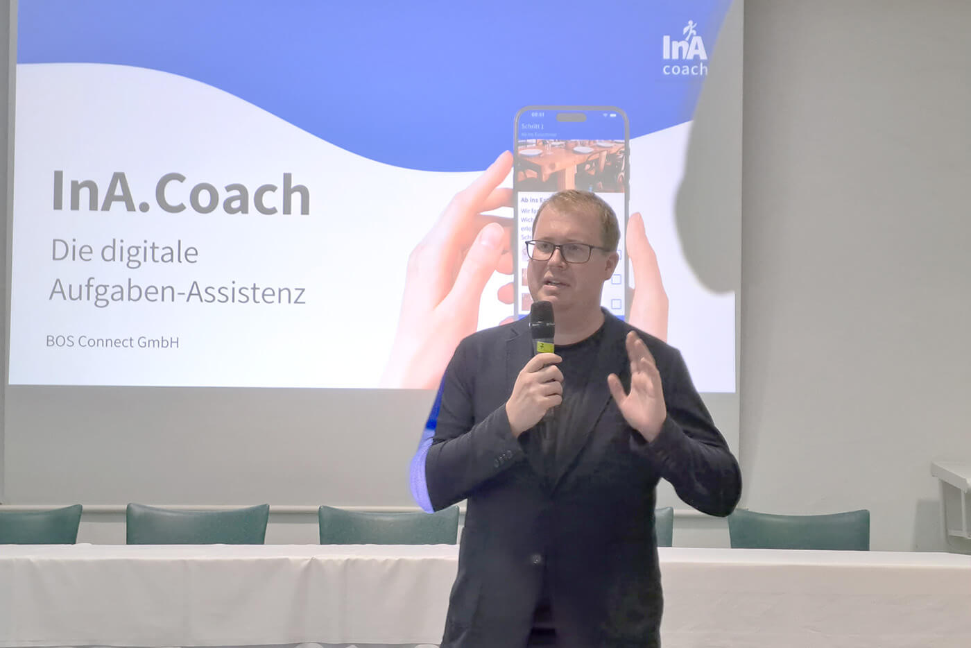 Auf einer Bühne präsentiert ein Mann die neue InA.Coach-App.