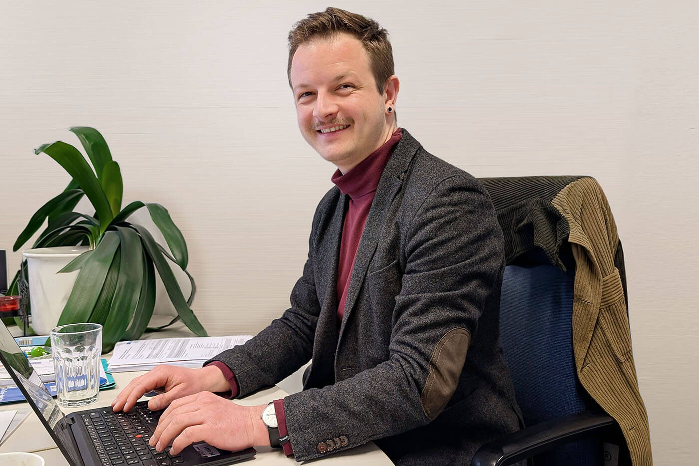 Porträtbild Daniel Krämer l © Monika Kleusch Aufnahme von Daniel Krämer an seinem Büroschreibtisch, vor ihm steht ein aufgeklappter Laptop.