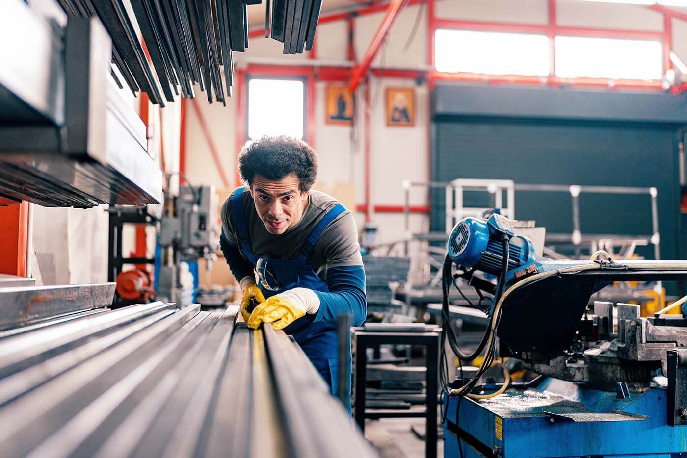 Auszubildender an einer Industriesäge l © 2023 f.t.Photographer/Shutterstock Ein junger Mann schiebt eine Leiste in eine Industriesäge.
