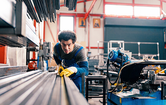 Ein junger Mann schiebt eine Leiste in eine Industriesäge.