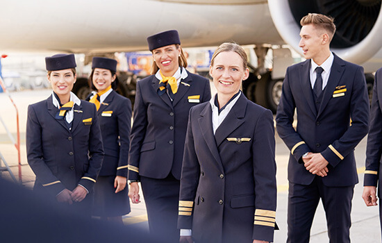 Gruppenbild einer Flugzeugbesatzung am Flughafen vor einem Flugzeug.