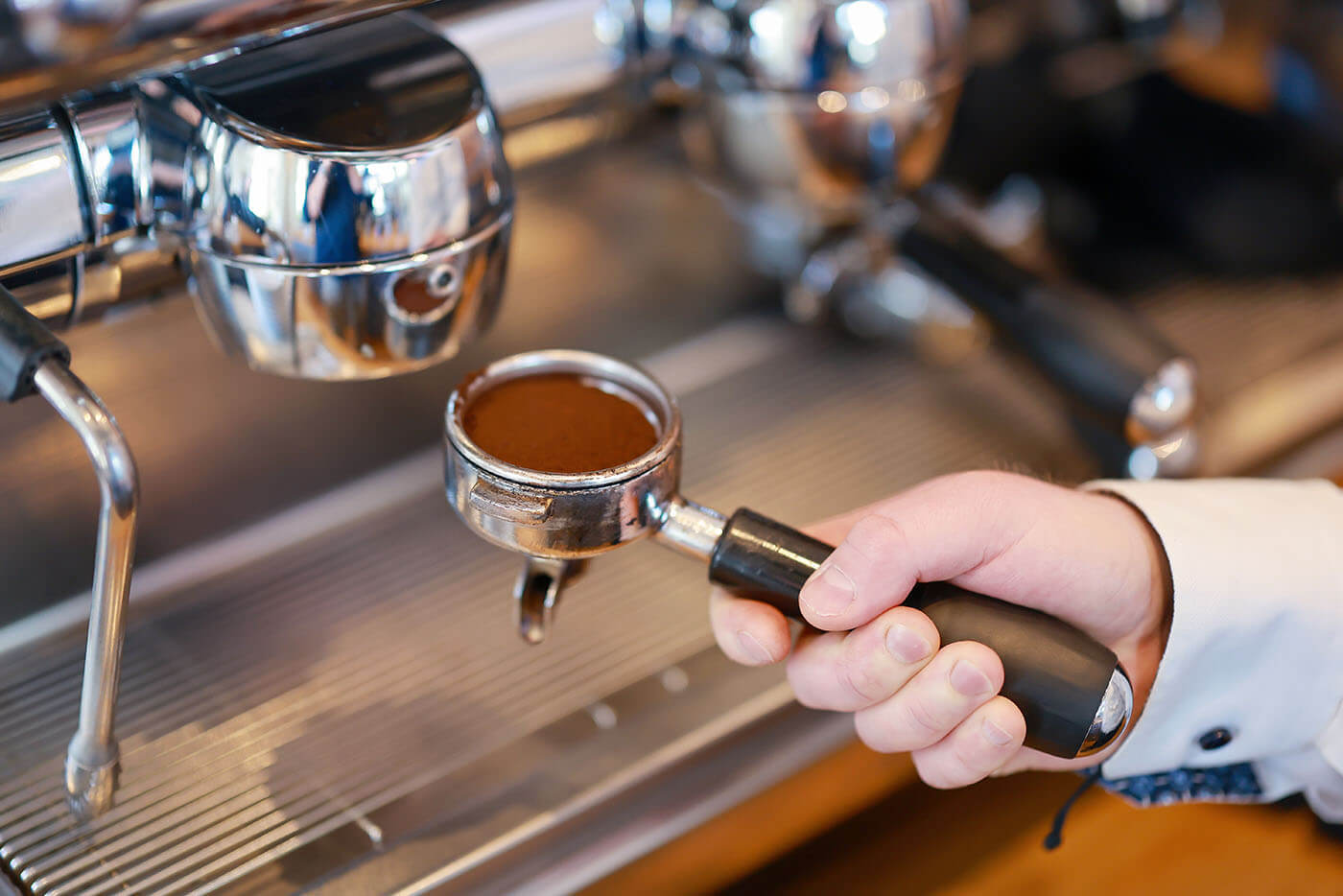 Hotel Villa Stern Kaffeezubereitung l © Rupert Oberhäuser Nachaufnahme eines Siebträgers mit frischgemahlenem Kaffeepulver, der gerade in die Kaffeemaschine eingesetzt wird.