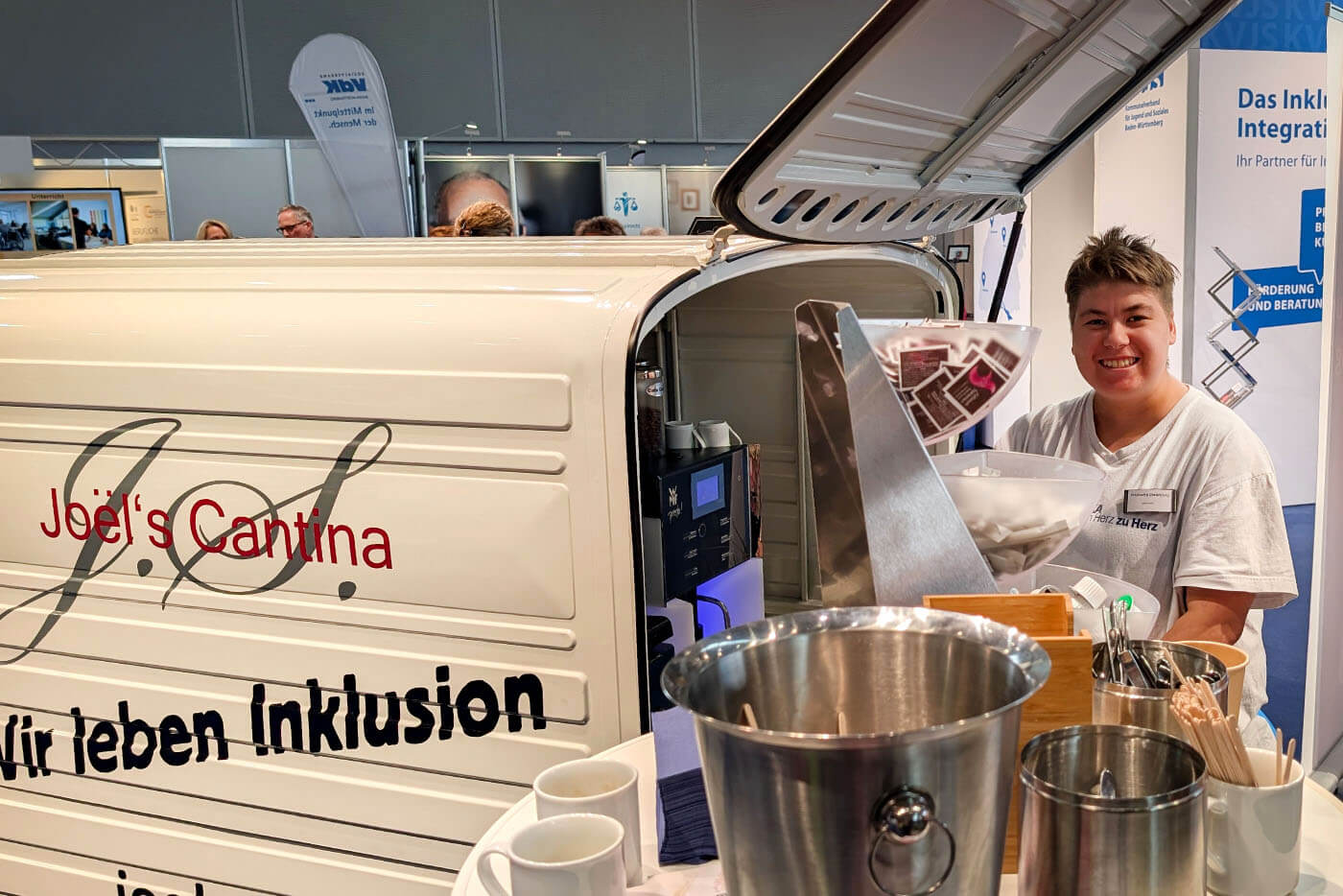 Eine Frau verkauft Kaffee aus einem Kaffee-Wagen.