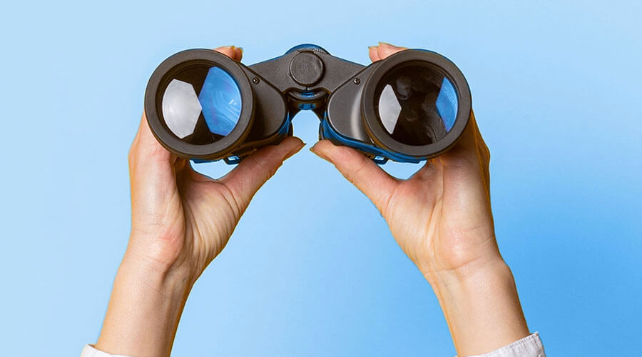 Fernglas Schmuckbild | © SAG stock/Shutterstock Ein Fernglas das von zwei Händen gehalten wird.