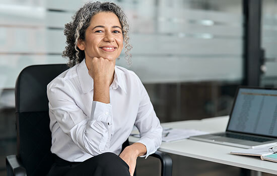 Eine Frau die in einem Büro am Schreibtisch sitzt. 