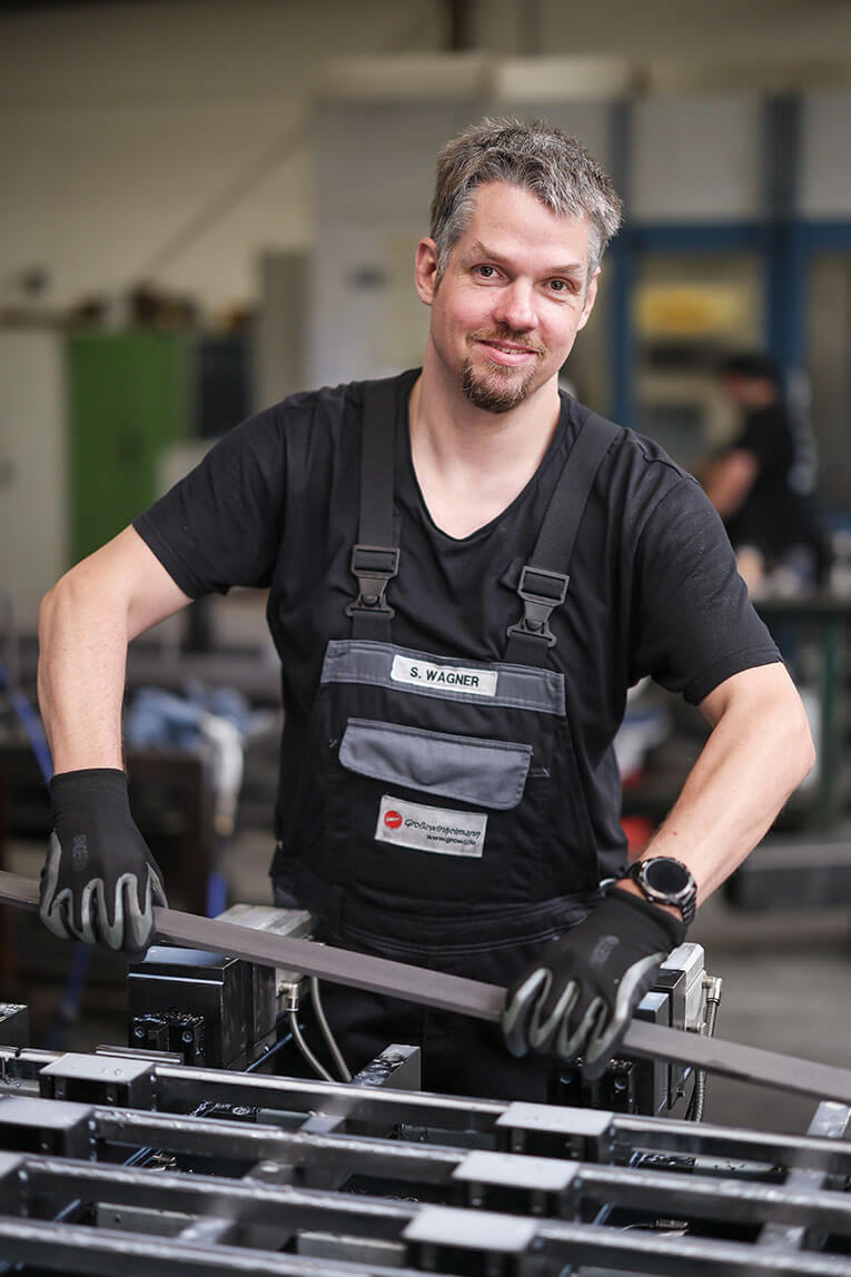 Ein Arbeiter der eine Metallleiste in der Hand hält.