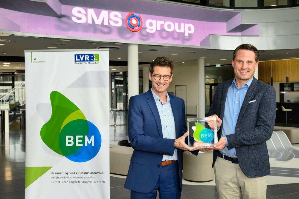 Christoph Beyer (LVR, li.) und Tobias Kox (SMS, re.) | © Dietrich Hackenberg/LVR Das Foto zeigt zwei Männer, die zusammen eine Prämie hochhalten. Auf der Prämie steht "BEM".
