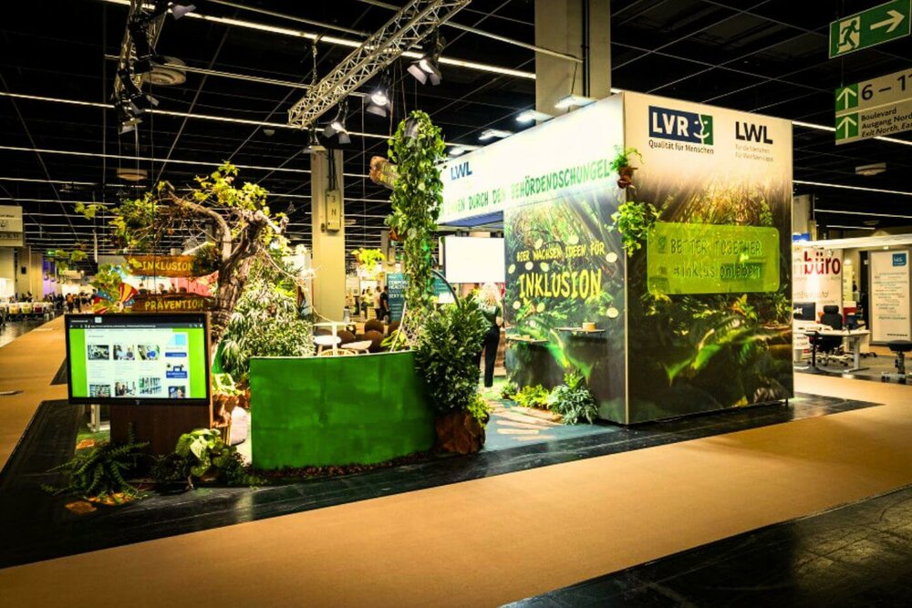 Der ZP-Europe-Messestand von LVR und LWL | © Heike Fischer/LVR Das Foto zeigt den Messestand von LVR und LWL auf der Messe Zukunft Personal Europe. Der Stand ist mit vielen Pflanzen wie ein Behördendschungel gestaltet.